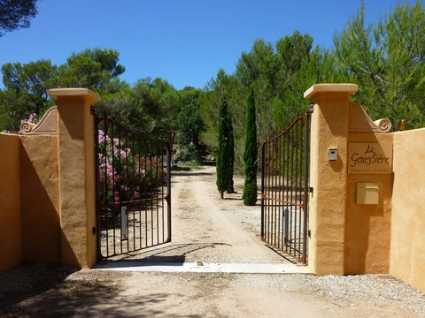 Le portail s'ouvre sur une allée bordée de lauriers roses.